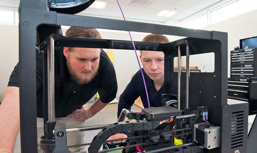 2 Students looking at machine in maker lab