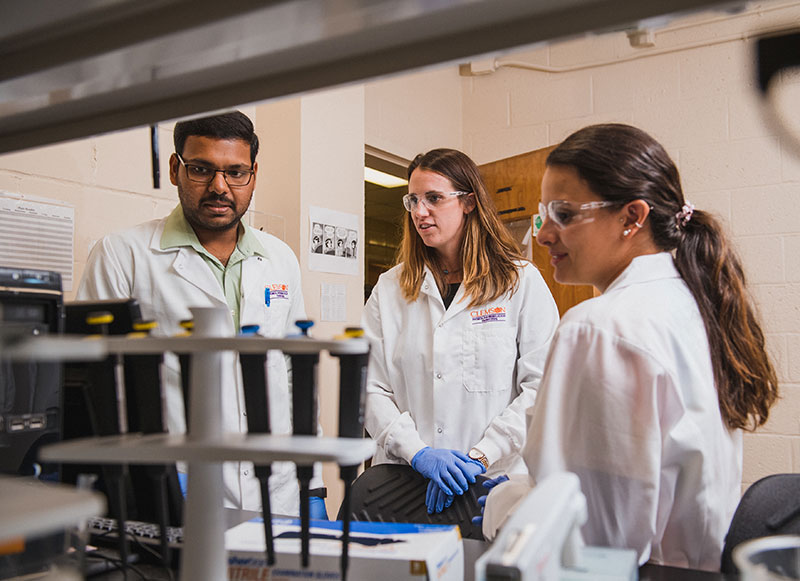 Female faculty member standing with two graduate students in a lab in Earle Hall.
