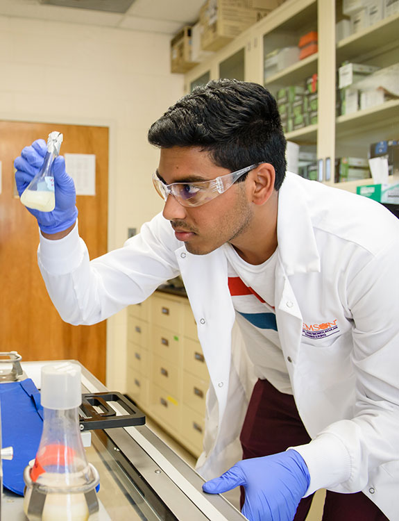Male student who was awarded fellowship is in lab performing research.