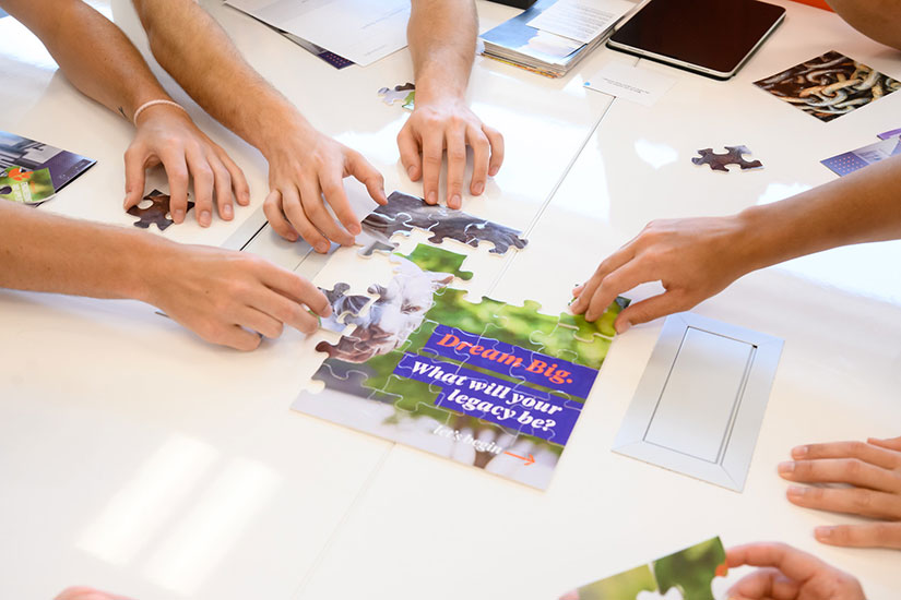 Students piecing puzzle together that says Dream Big.