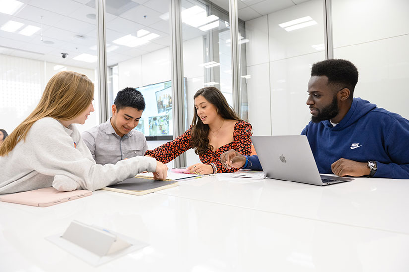 Two males and two females sit around table in Watt Center working.