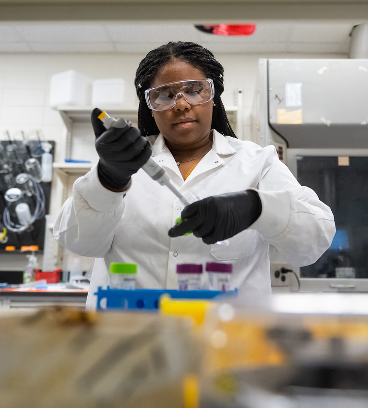 Female student in lab with safety glasses on.