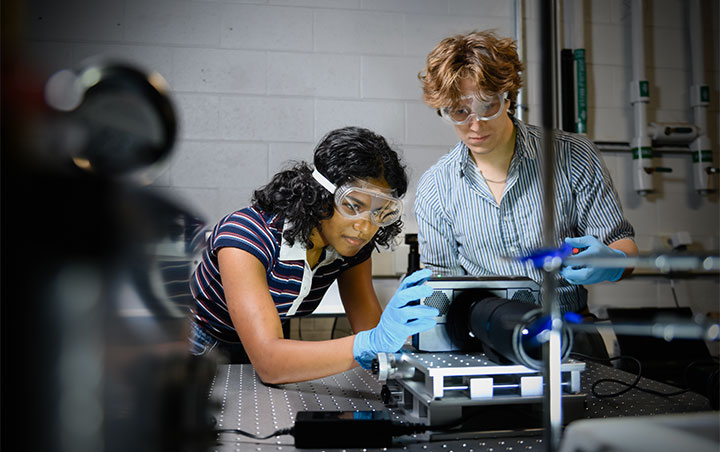 Upperclassman engineering students helping first-year engineering student with research project.