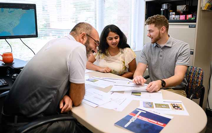 Engineering professor in office talking to two students about real applications of research.
