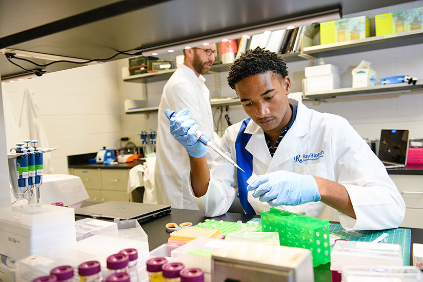 Student with vials in lab with faculty member