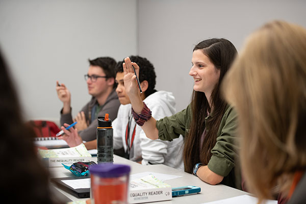 Honors class with smiling student raising hand