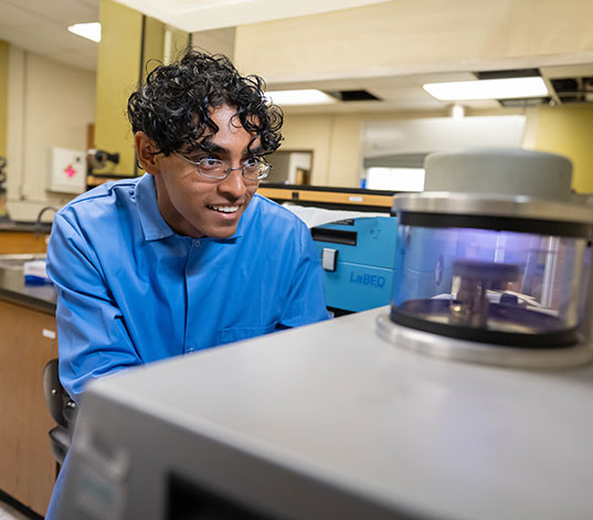 Student peering at large equipment in the lab.