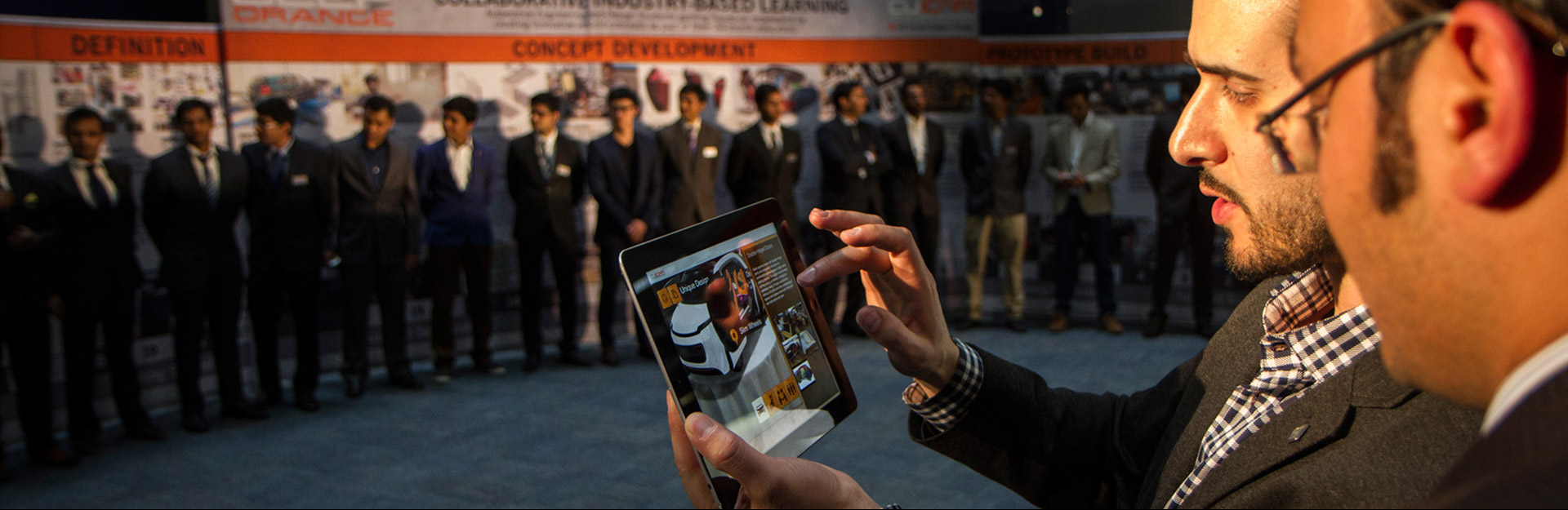 Two individuals discuss images on an iPad while others look on