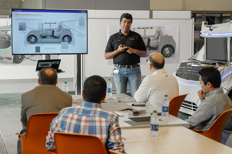 Student stands in front of a group presenting details of the DO10 Vehicle