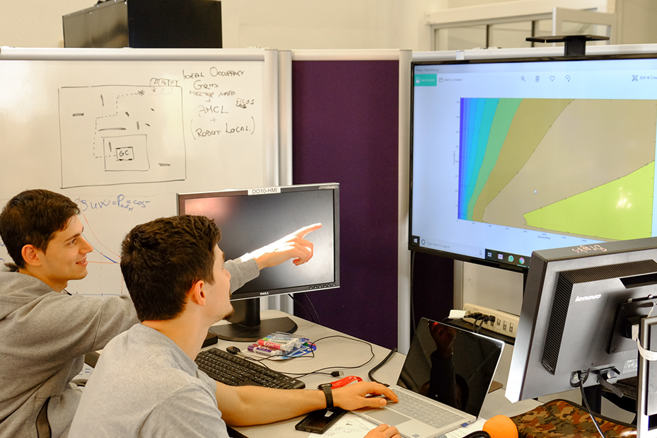 Two students study vehicle details on a monitor