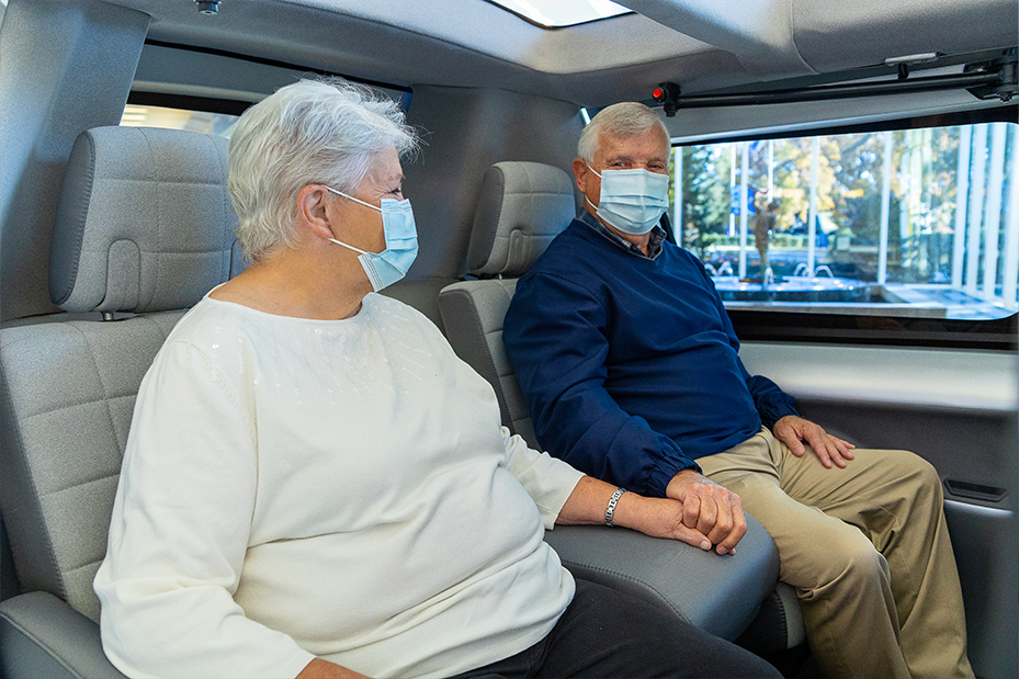 An older couple sit holding hands in the DO10 vehicle