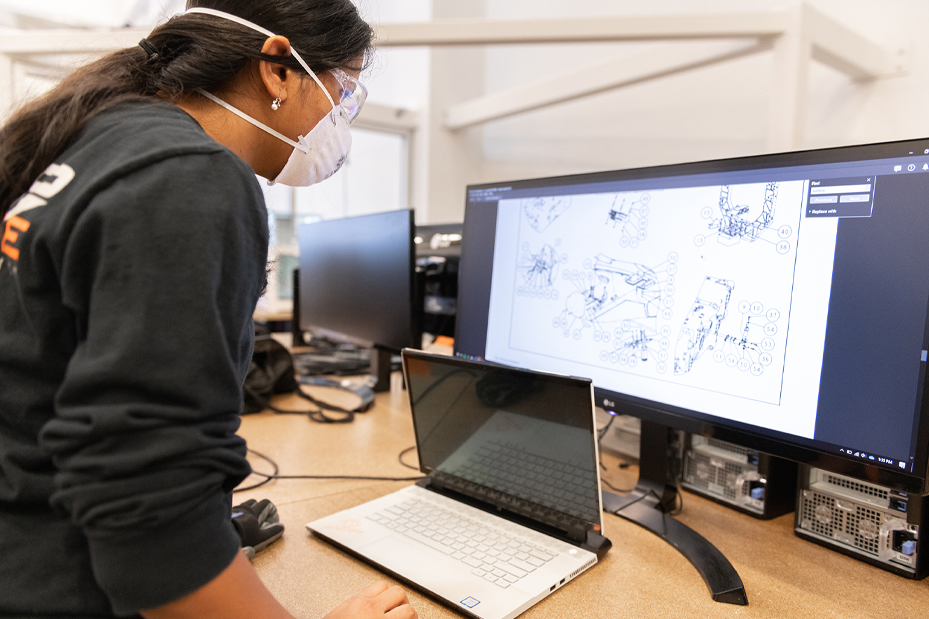 Female DO12 student looking at vehicle schematics on a computer