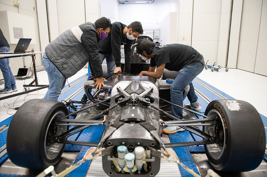 Close-up of vehicle with DO12 team in background
