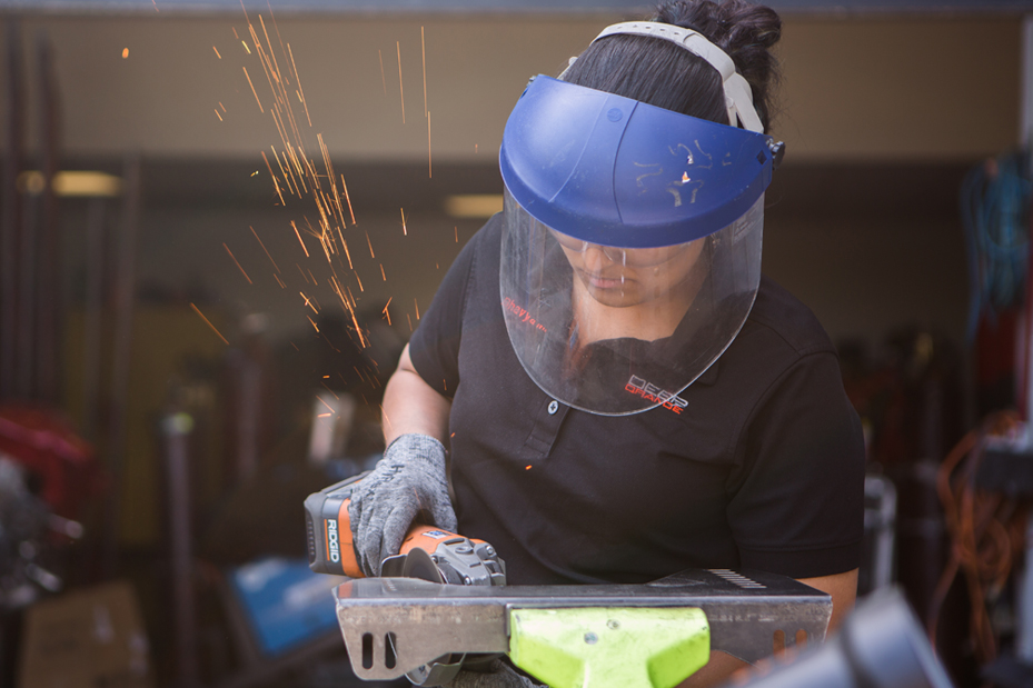 Female students works with a power tool with sparks flying