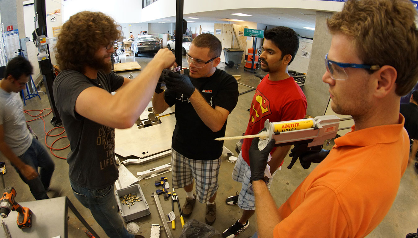 Students work with an industry representative on a vehicle component