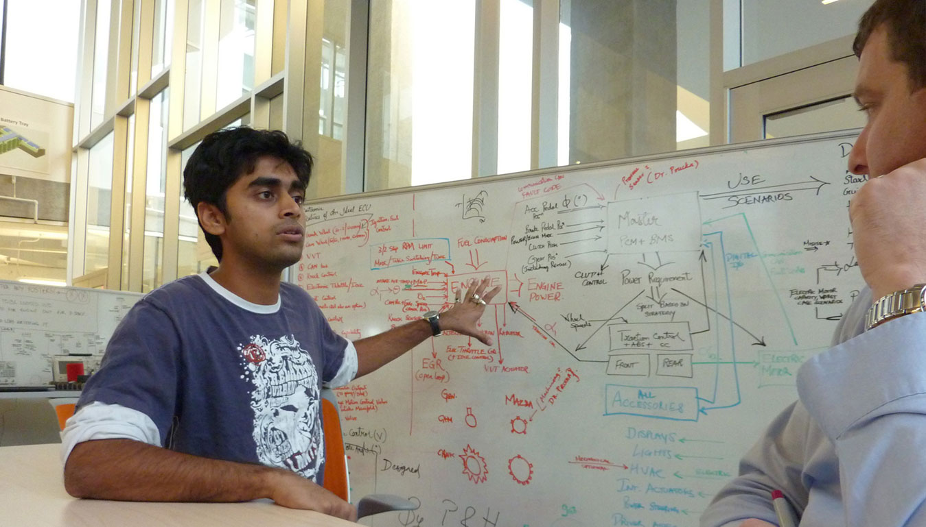 Male student explains his project whiteboard to his professor