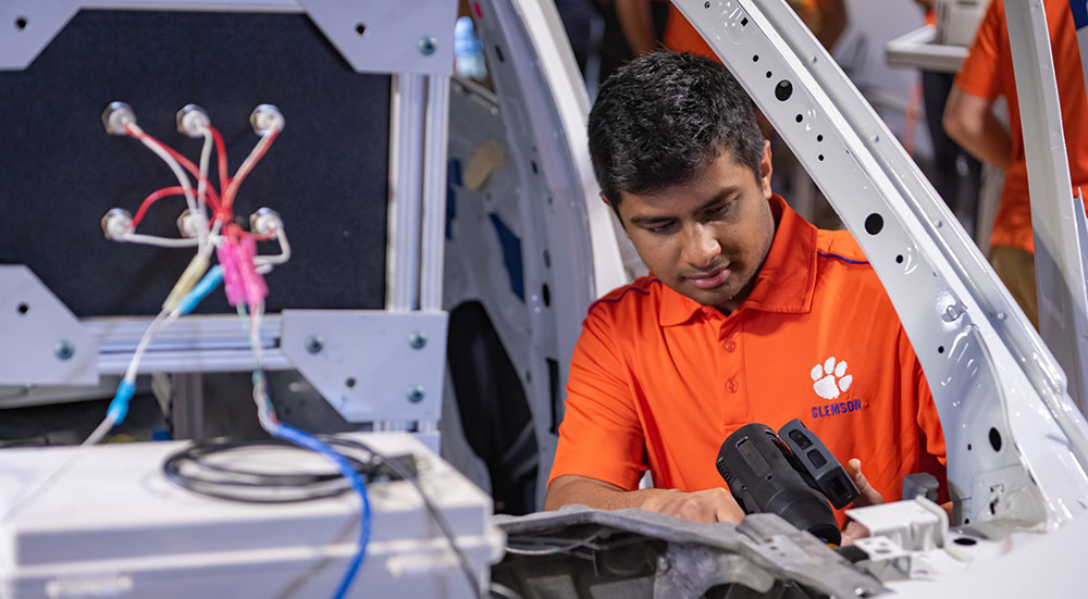 Student working on white car frame at CUICAR.