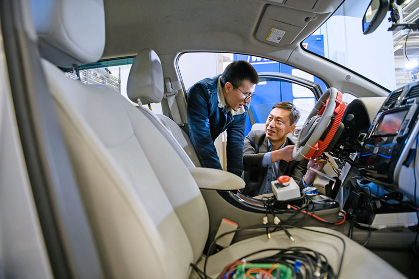 Yunyi Jia with student working on vehicle.