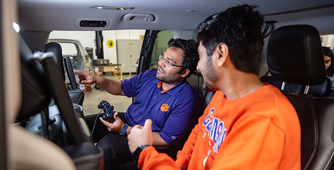 Two students in car testing computer system.