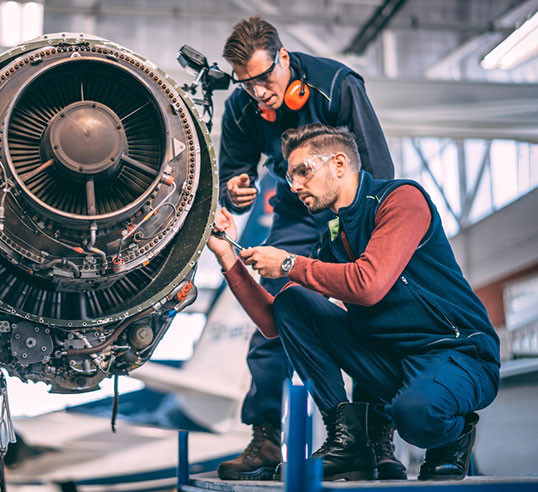 Two people beside aircraft working.