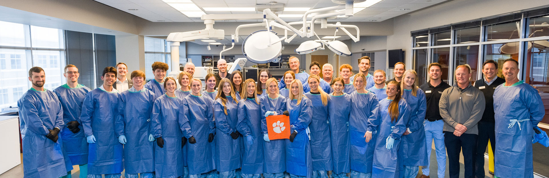 Group shot of students and doctors in lab holding Clemson Tiger Rag