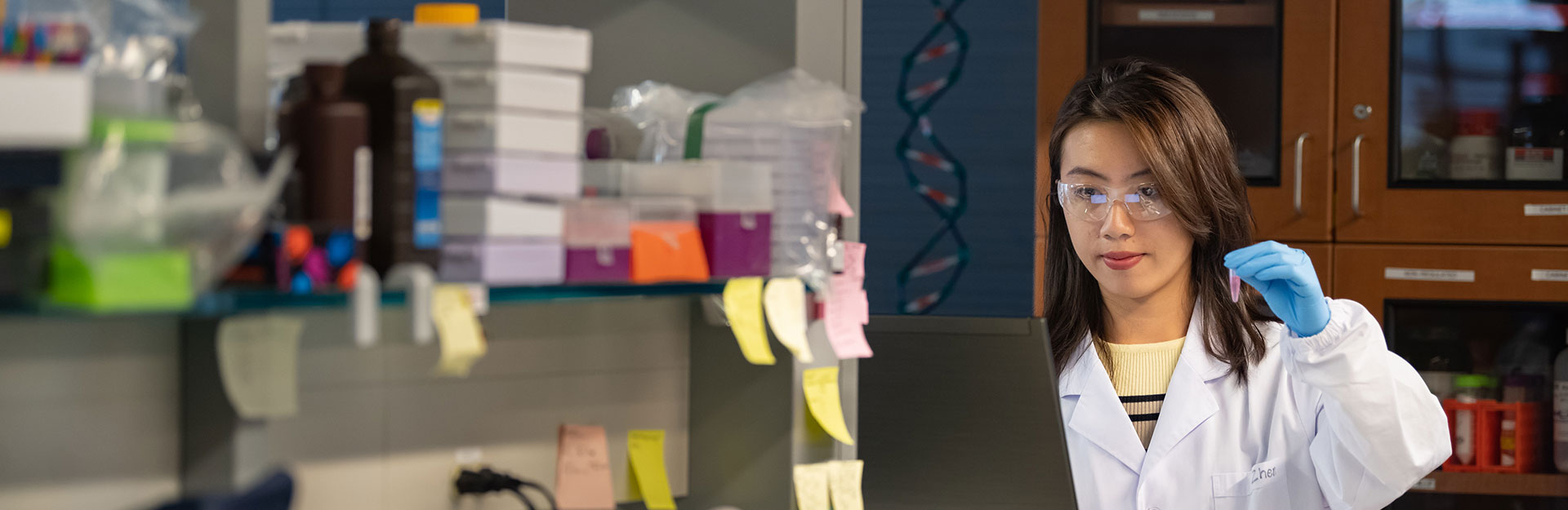 Team member holding vial while checking against data on screen.