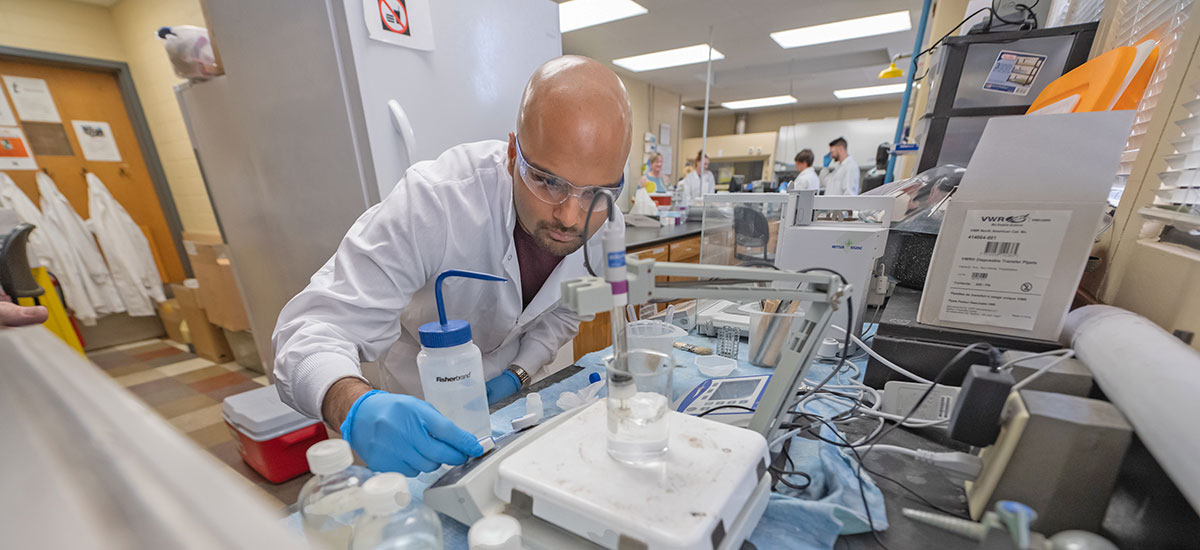 Student in research lab with more students in background