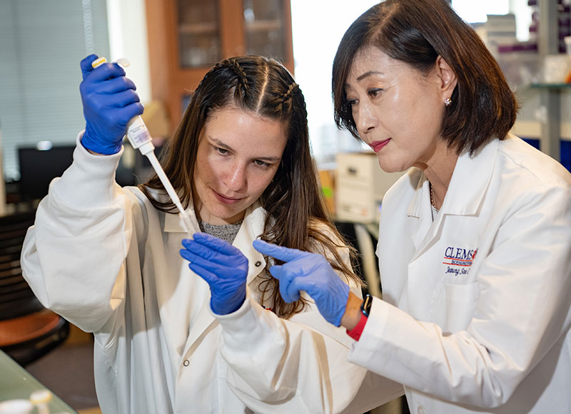 Jeong Soo Lee assisting student with pipetting into a vial in Greenville lab