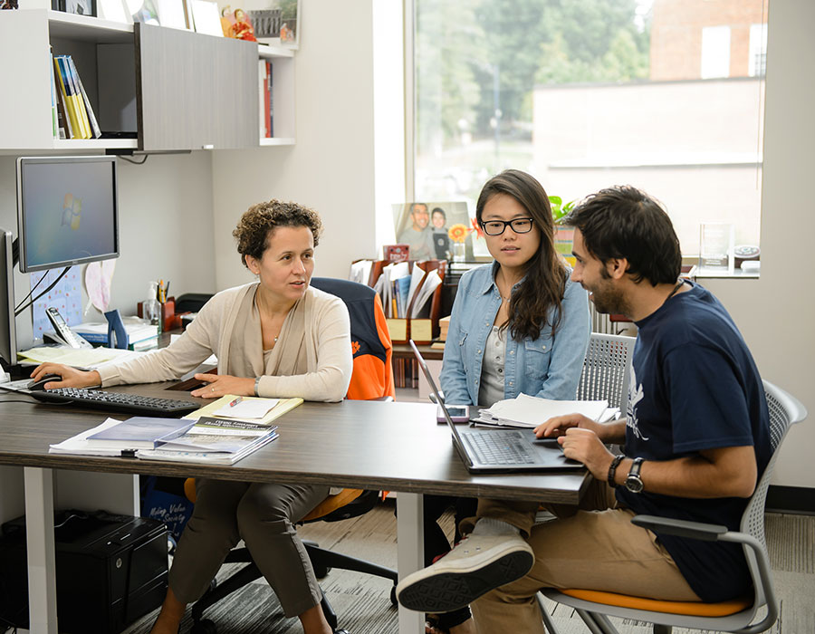 Eksioglu having a discussion with male and female students in office.