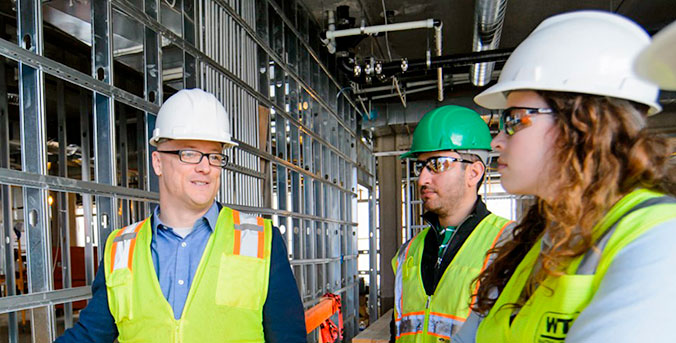 Faculty with students on construction site.