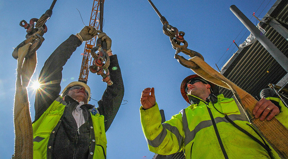 Two males in construction protection gear working together during Watt construction.