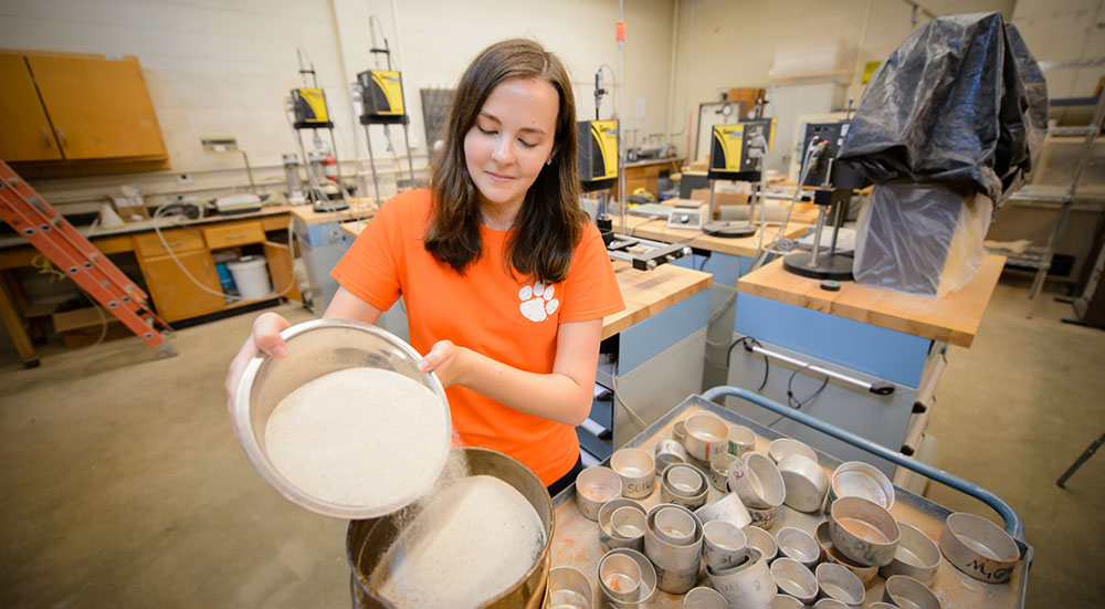 Female student in lab mixing powder.