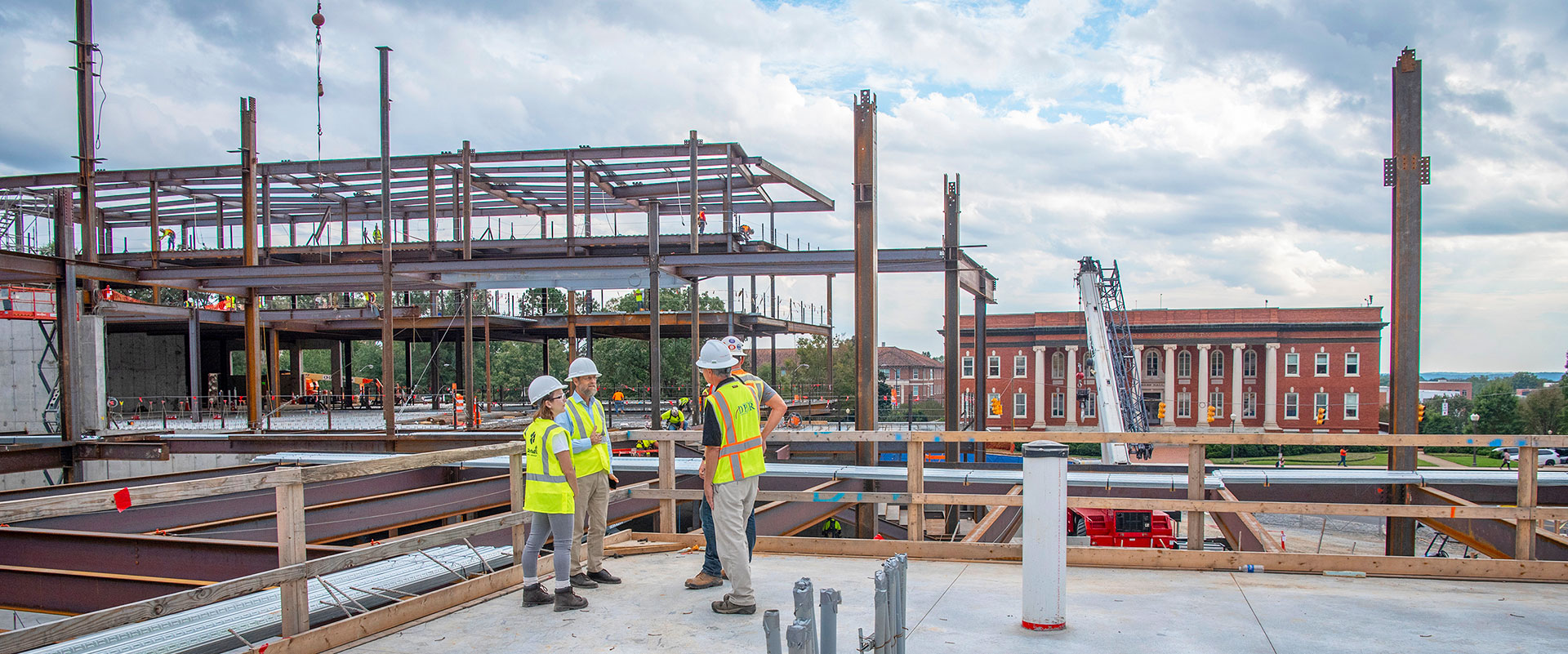 Group in hard hats on construction site with Sikes Hall in the background.