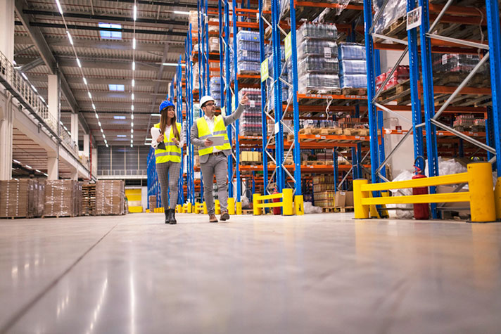 Male and female walk through manufacturing area with tablet.