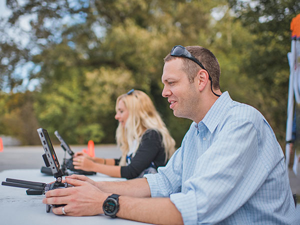 Male and female using remotes to drive drone.