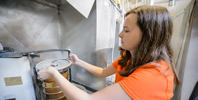 Female in lab with cement mixture.