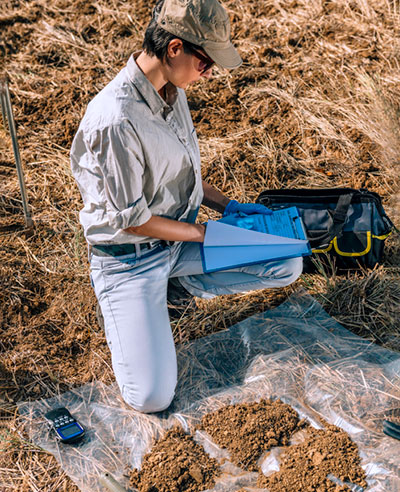 Female taking soil samples and writing down data.