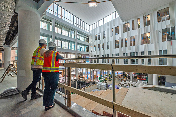 Male and female looking up inside building undergoing finishing touches on build.