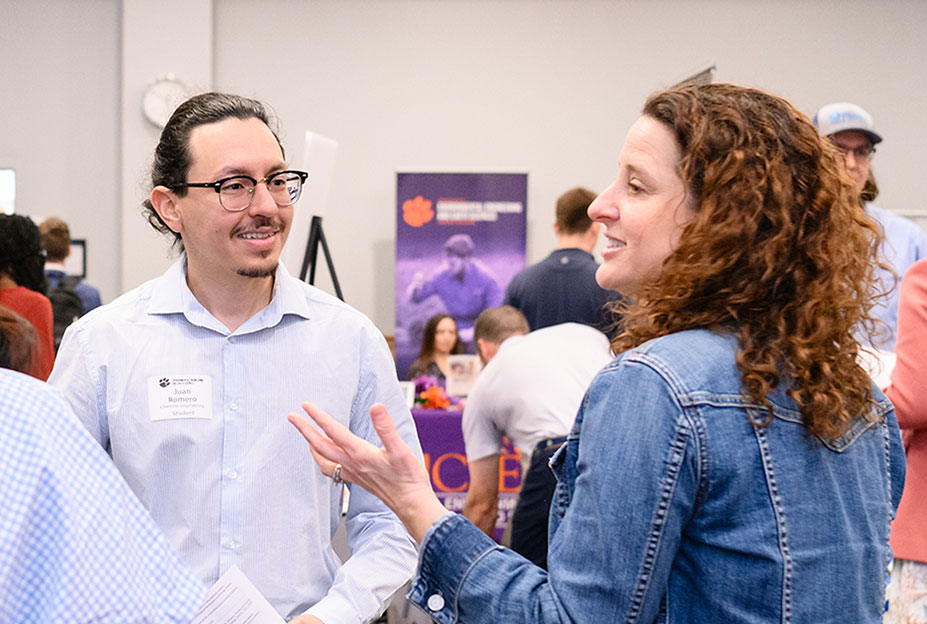 Career Fair event with student chatting with two industry representatives, while in the Hendrix Center
