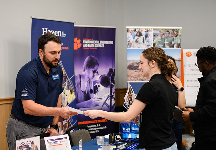 Career Fair Industry member looking over resume that student is handing him.