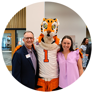 Duvall standing with a student mentee and the Clemson tiger mascot.