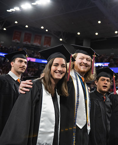 Graduates smiling at graduation ceremony.