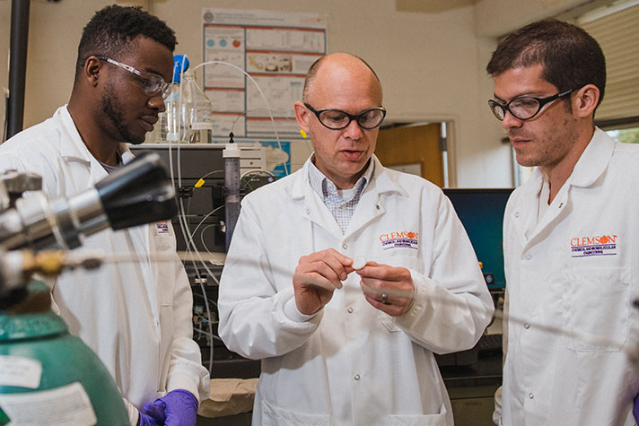 Husson with two students in lab.