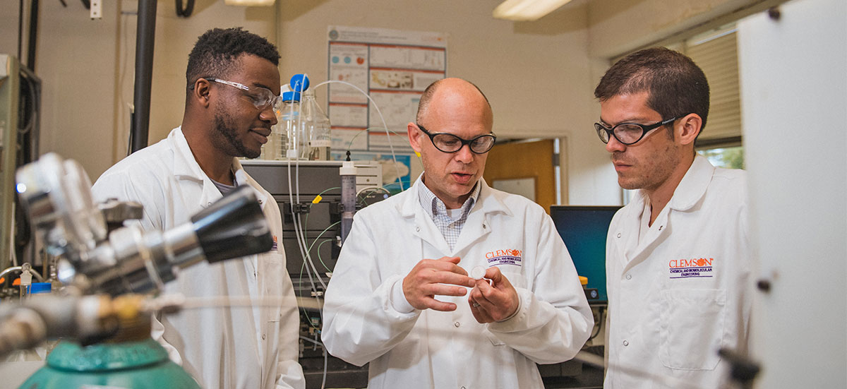 Husson with two graduate students in lab.