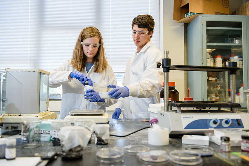 Two students in lab in protective gear.