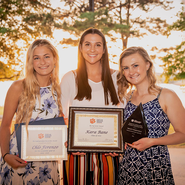 Three female students together holding their awards.