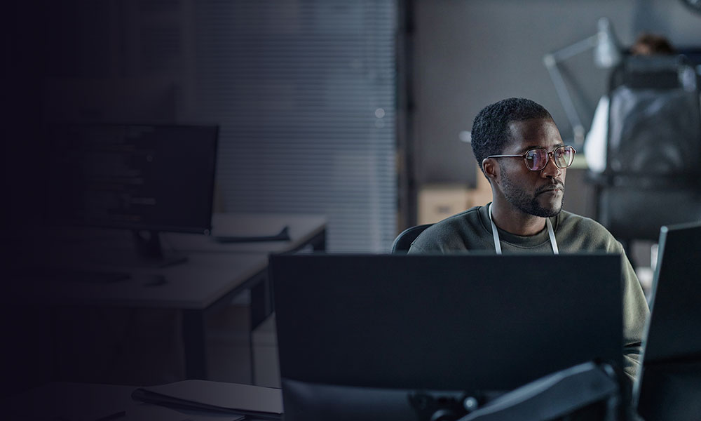 Man in office who is looking at his laptop, concentrating on work.