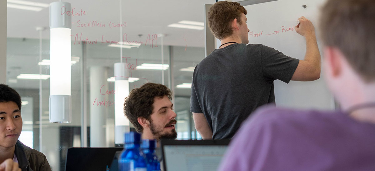 Students in Watt writing on whiteboard and glass