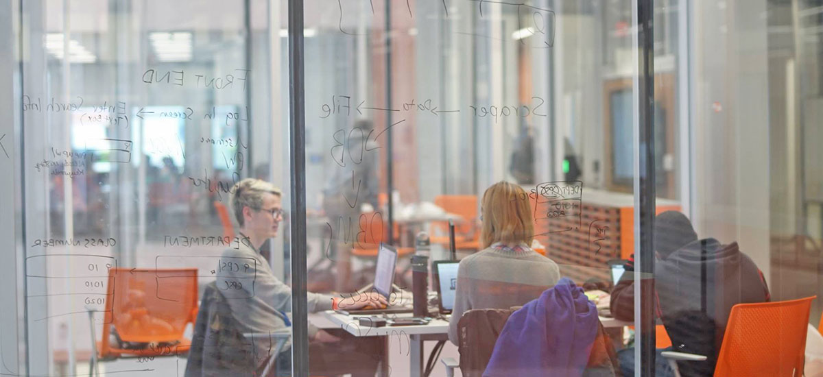 Students working and studying together, with writing on the glass walls.