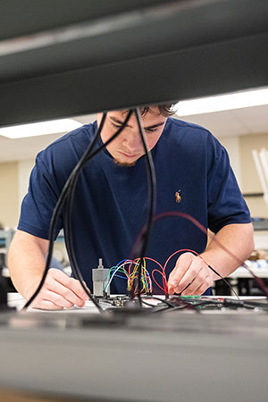 Student with electrical wires in lab